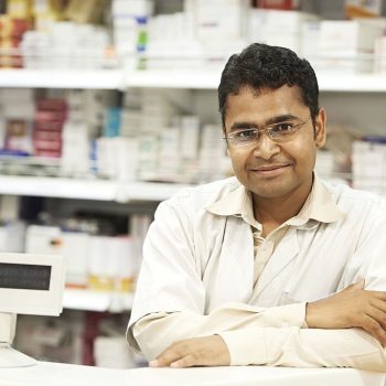 cheerful pharmacist chemist woman standing in pharmacy drugstore